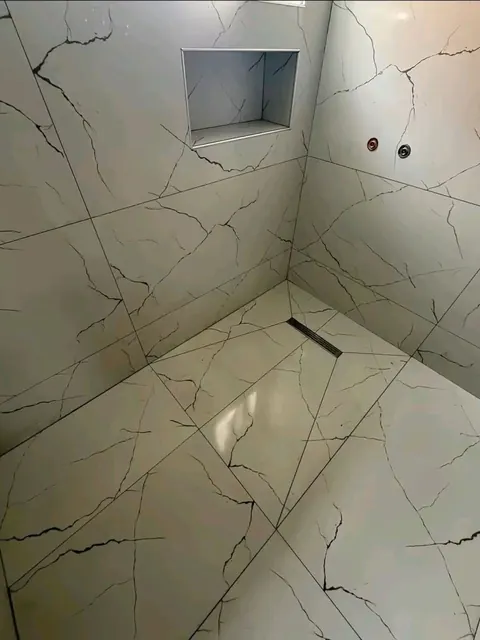 Baño reformado con ducha de obra, porcelánico efecto mármol, sumidero lineal y hornacina