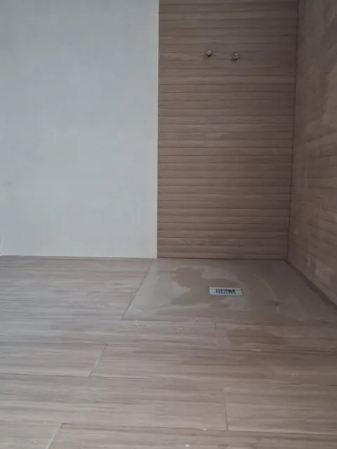 Baño con revestimiento porcelánico efecto madera y plato de ducha a ras de suelo